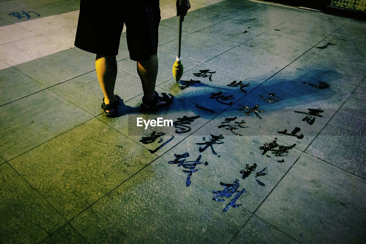 Low section of man doing calligraphy on floor