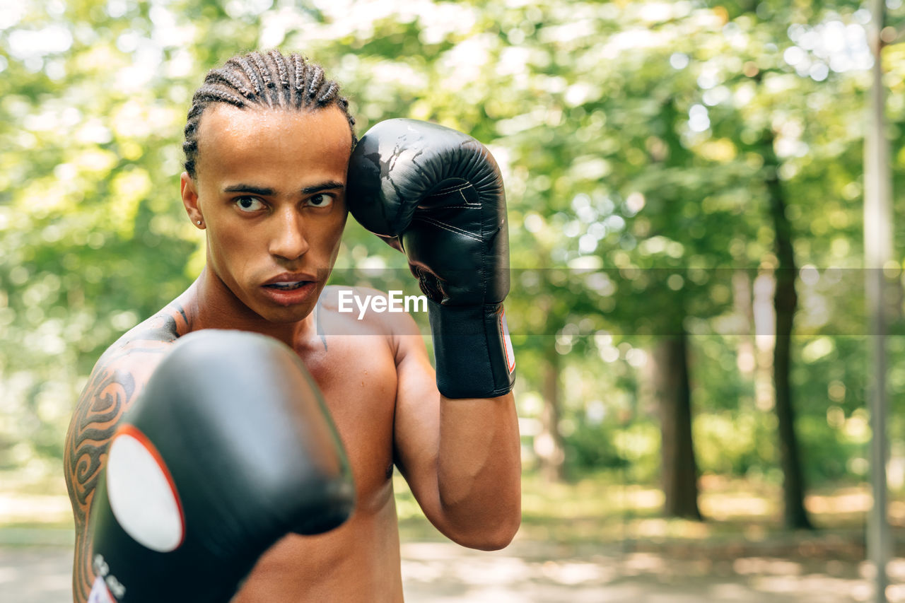 Portrait of shirtless man boxing on street