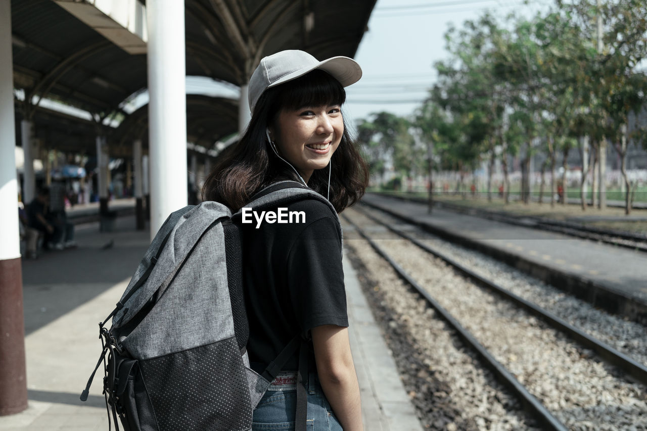 YOUNG WOMAN SMILING AT RAILROAD STATION