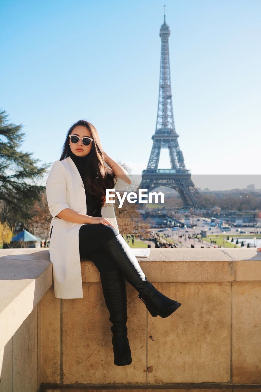 Portrait of smiling young woman sitting on eiffel tower