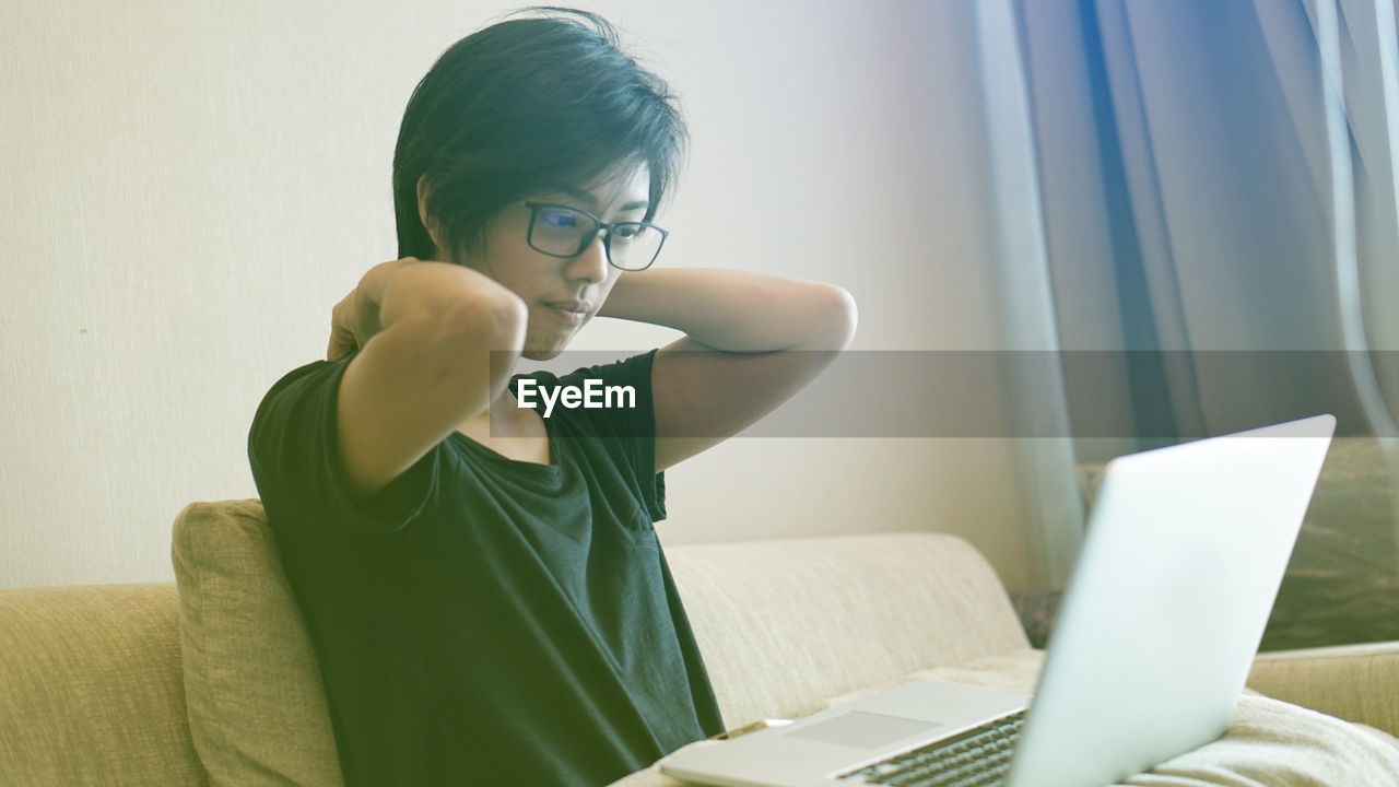 Woman using laptop while sitting on sofa at home