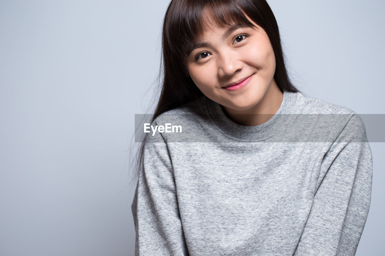 Smiling young woman against gray background