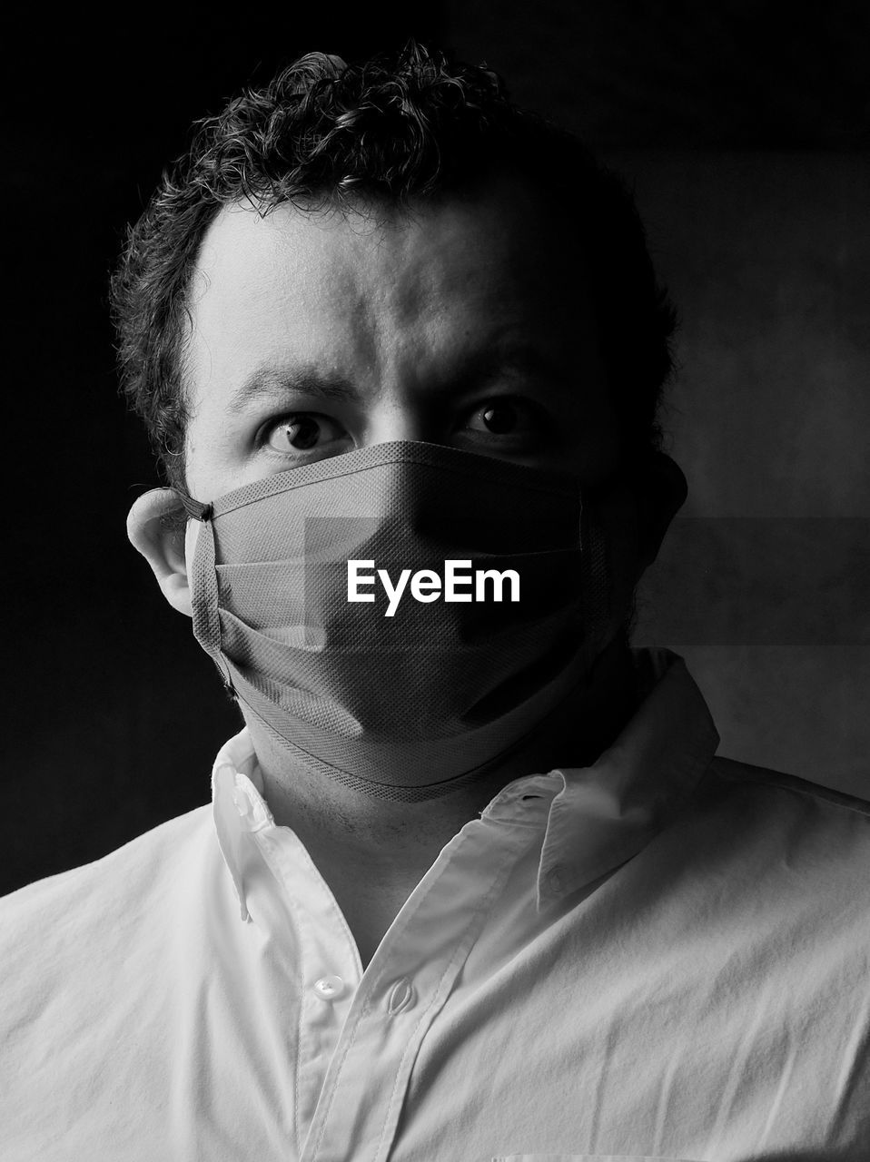 Close-up black and white portrait of young hispanic man wearing face mask. 