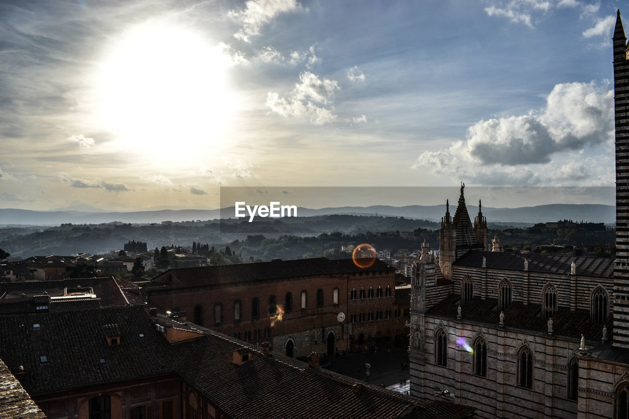 HIGH ANGLE VIEW OF BUILDINGS AGAINST CLOUDY SKY