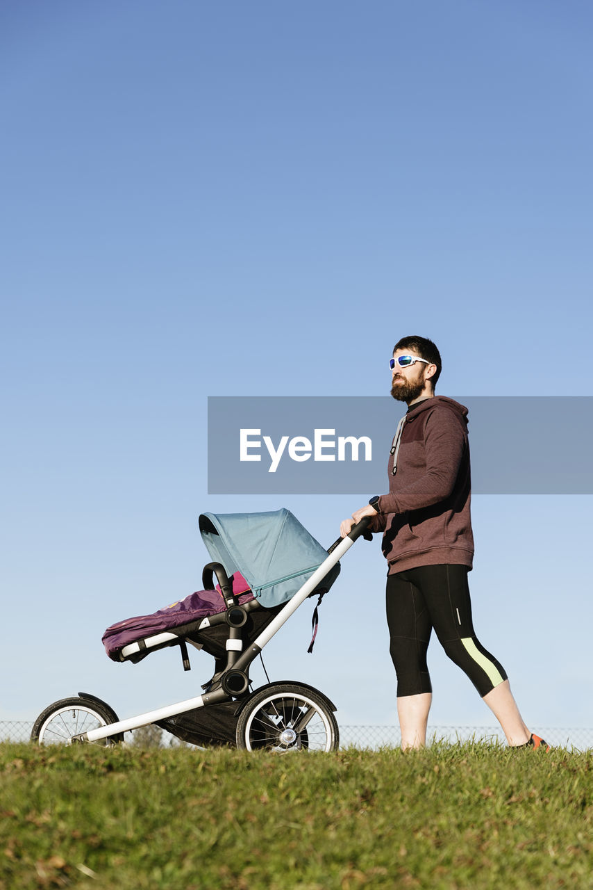 Low angle view of man walking with baby against sky