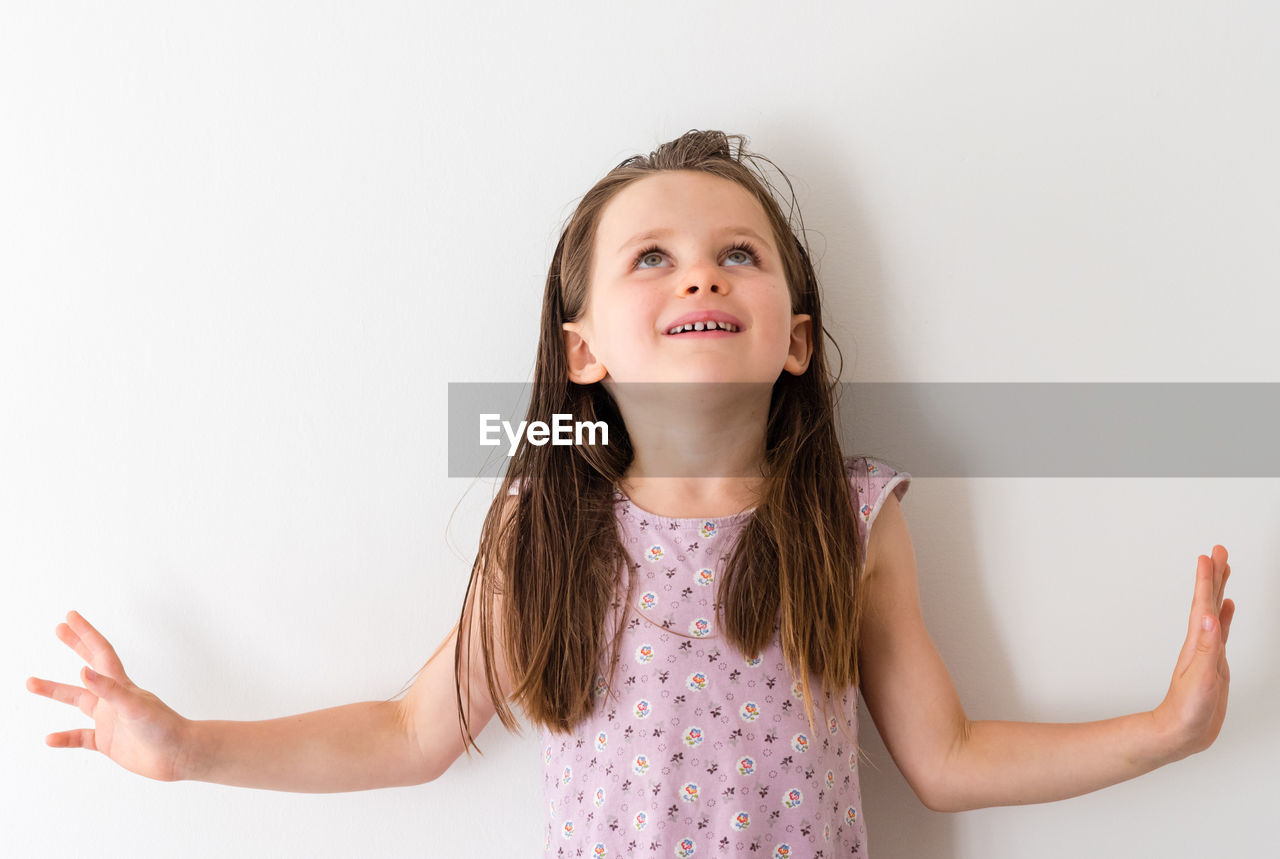 Smiling girl looking up while standing against white background