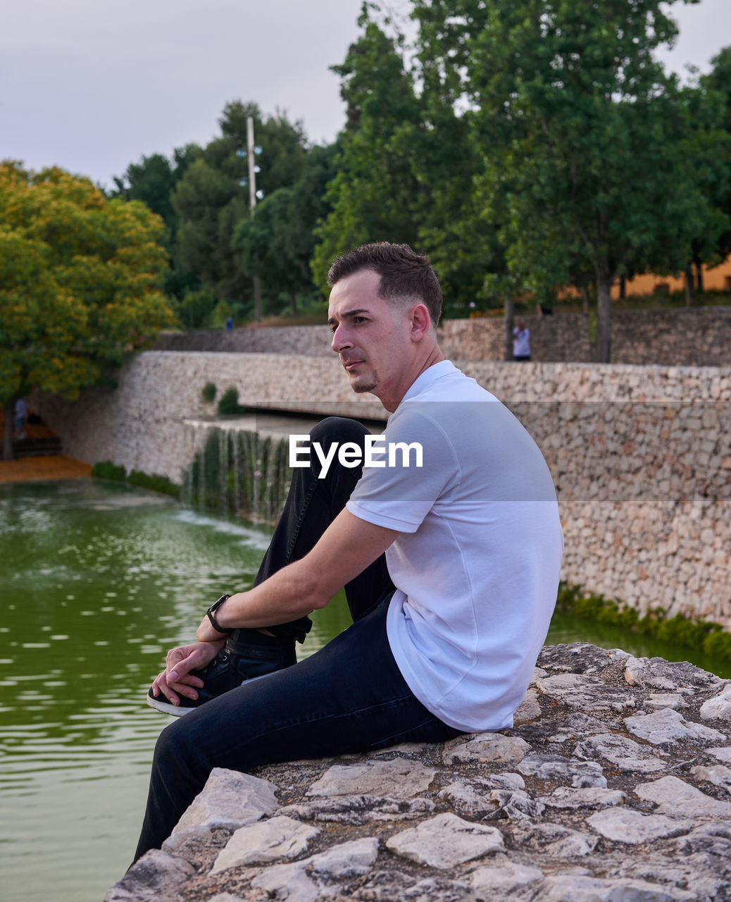 Portrait of young man sitting on retaining wall