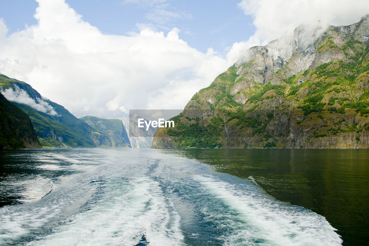 Scenic view of sea by mountains against sky