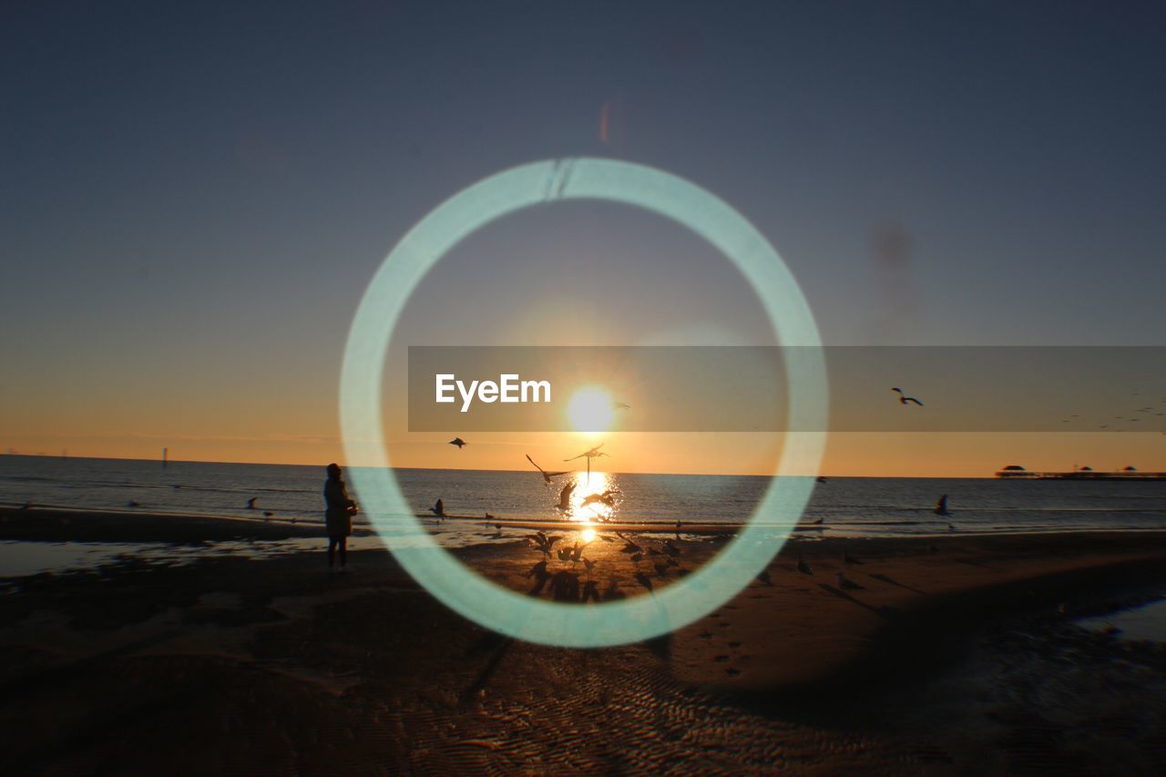 SCENIC VIEW OF BEACH AGAINST SKY AT SUNSET