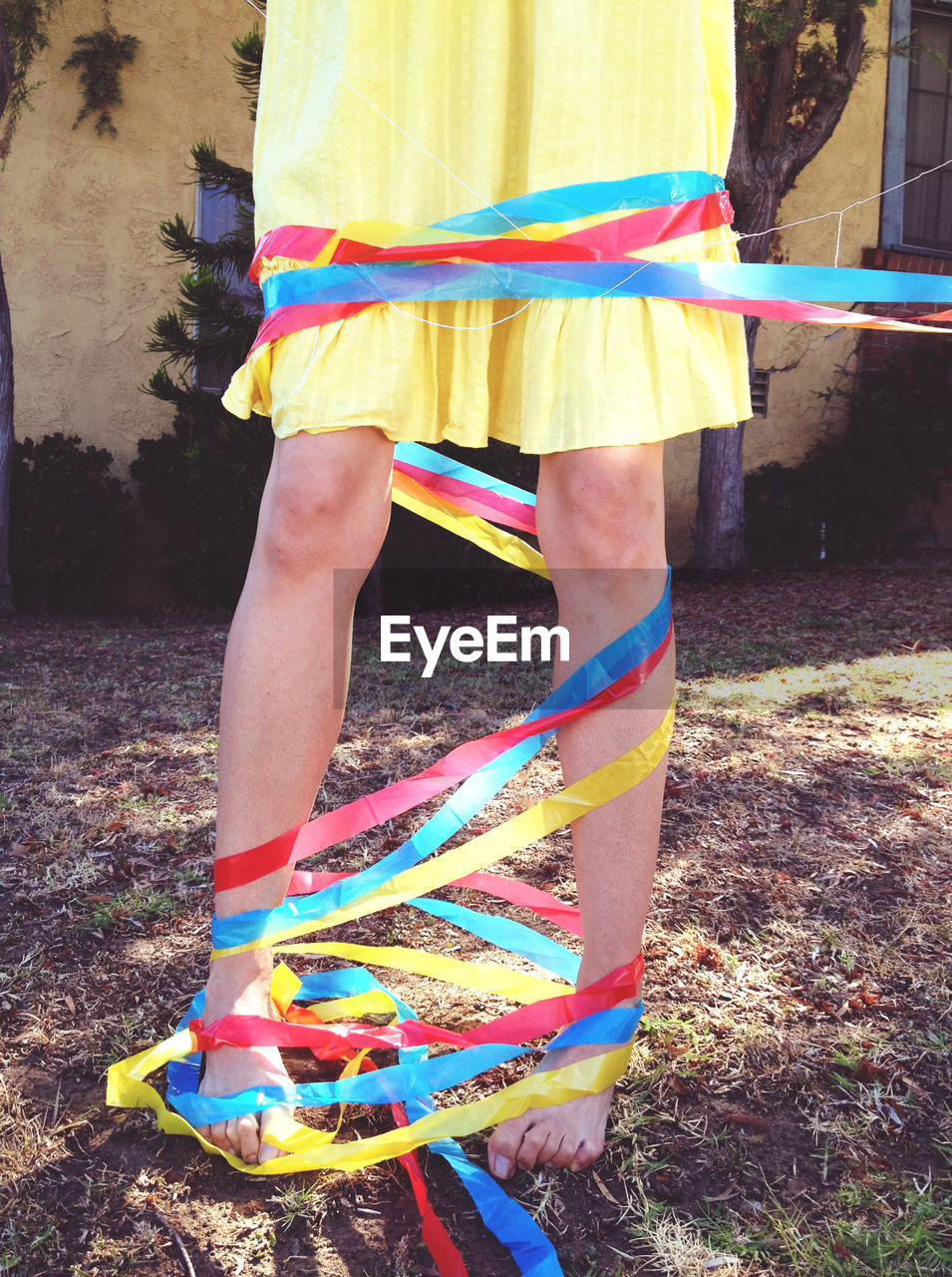 Low section of woman legs wrapped with colorful ribbons