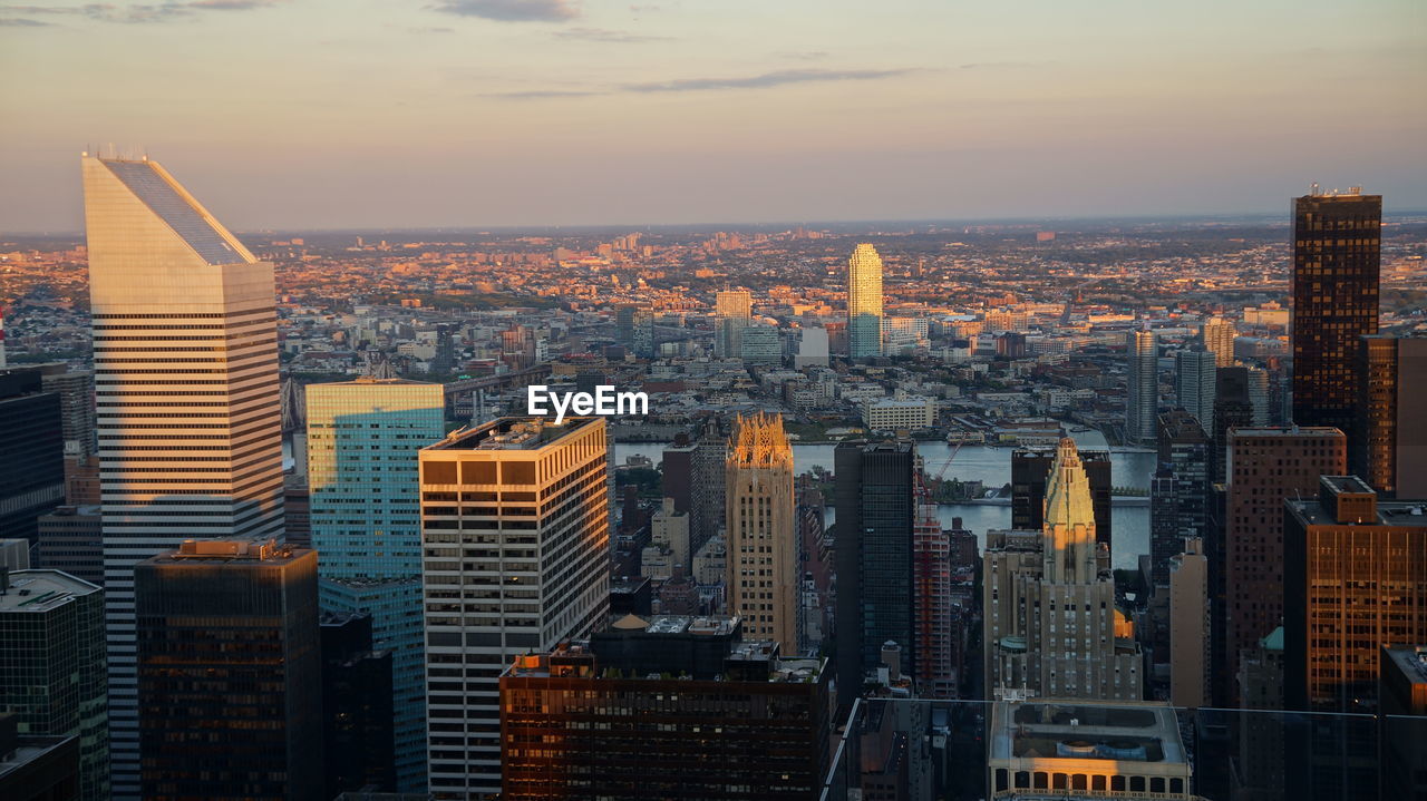 Aerial view of illuminated buildings in city against sky during sunset