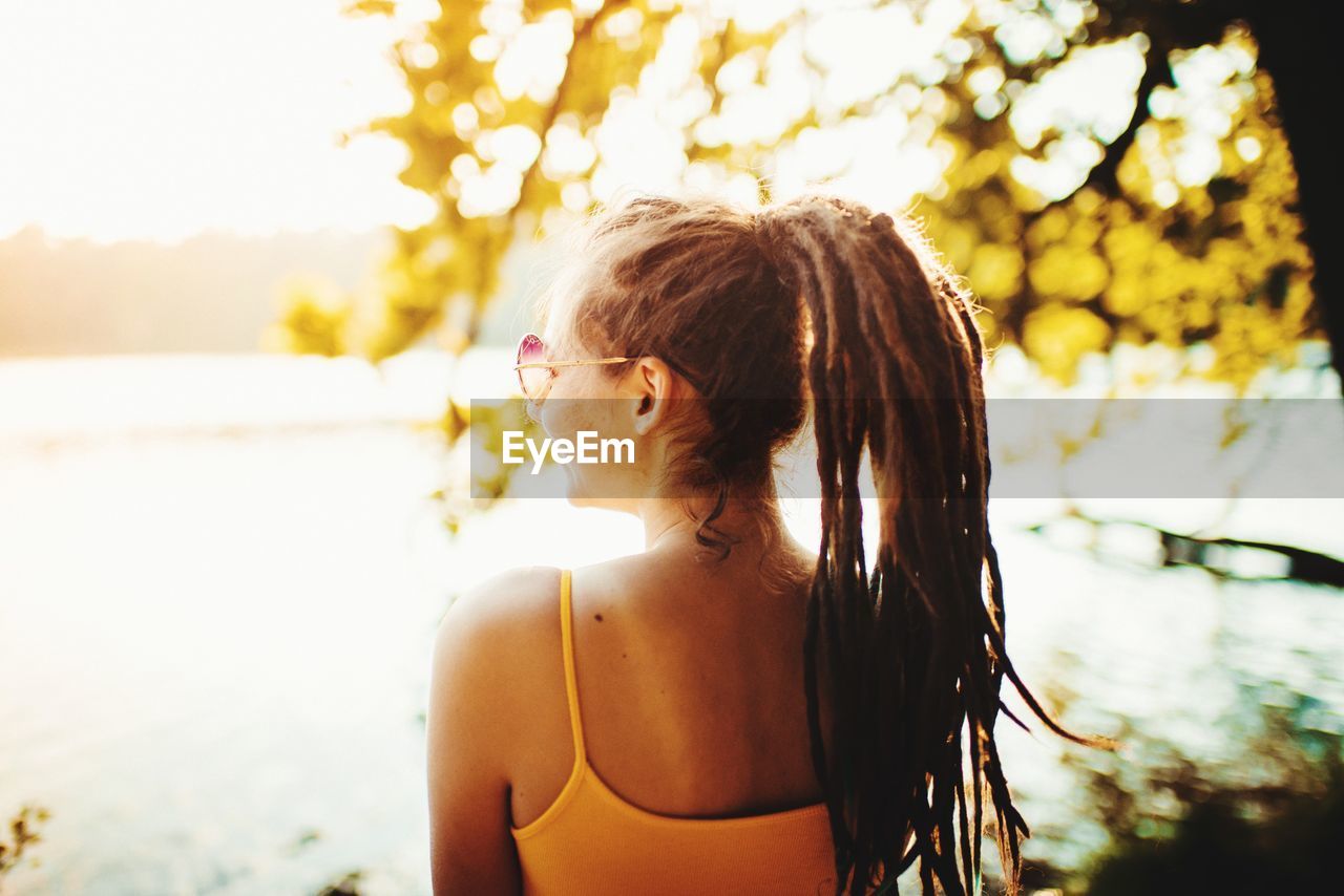 Young woman looking away while standing outdoors