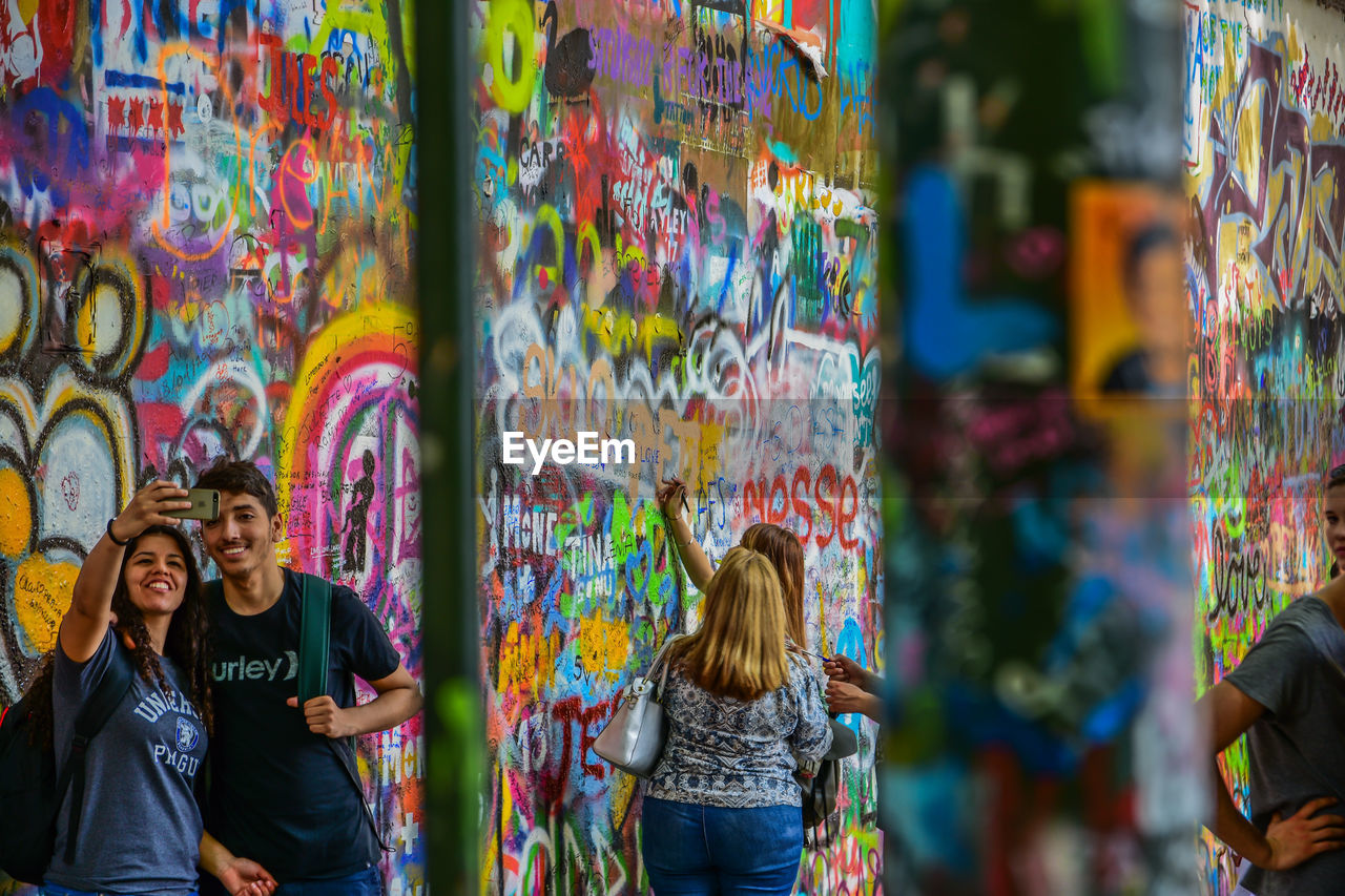 YOUNG WOMAN STANDING AGAINST GRAFFITI WALL