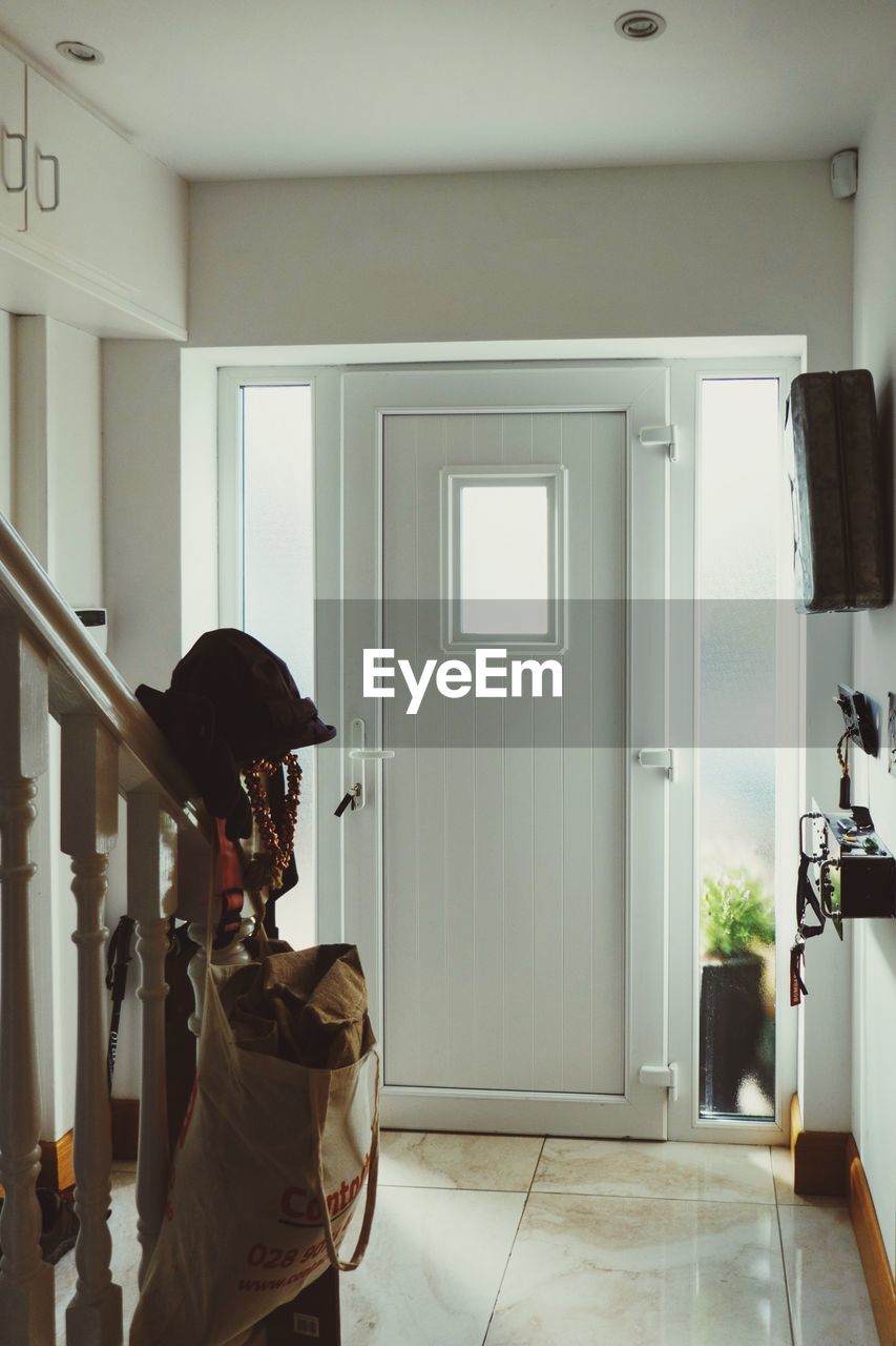 REAR VIEW OF WOMAN STANDING AT ENTRANCE OF HOME