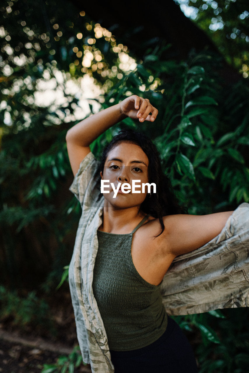 Latina girl with green shirt dancing surrounded by green leaves