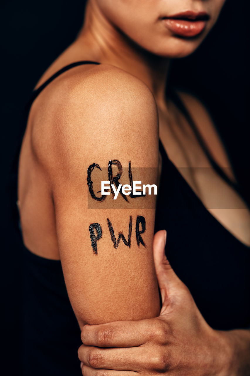 Midsection of woman with text on arm