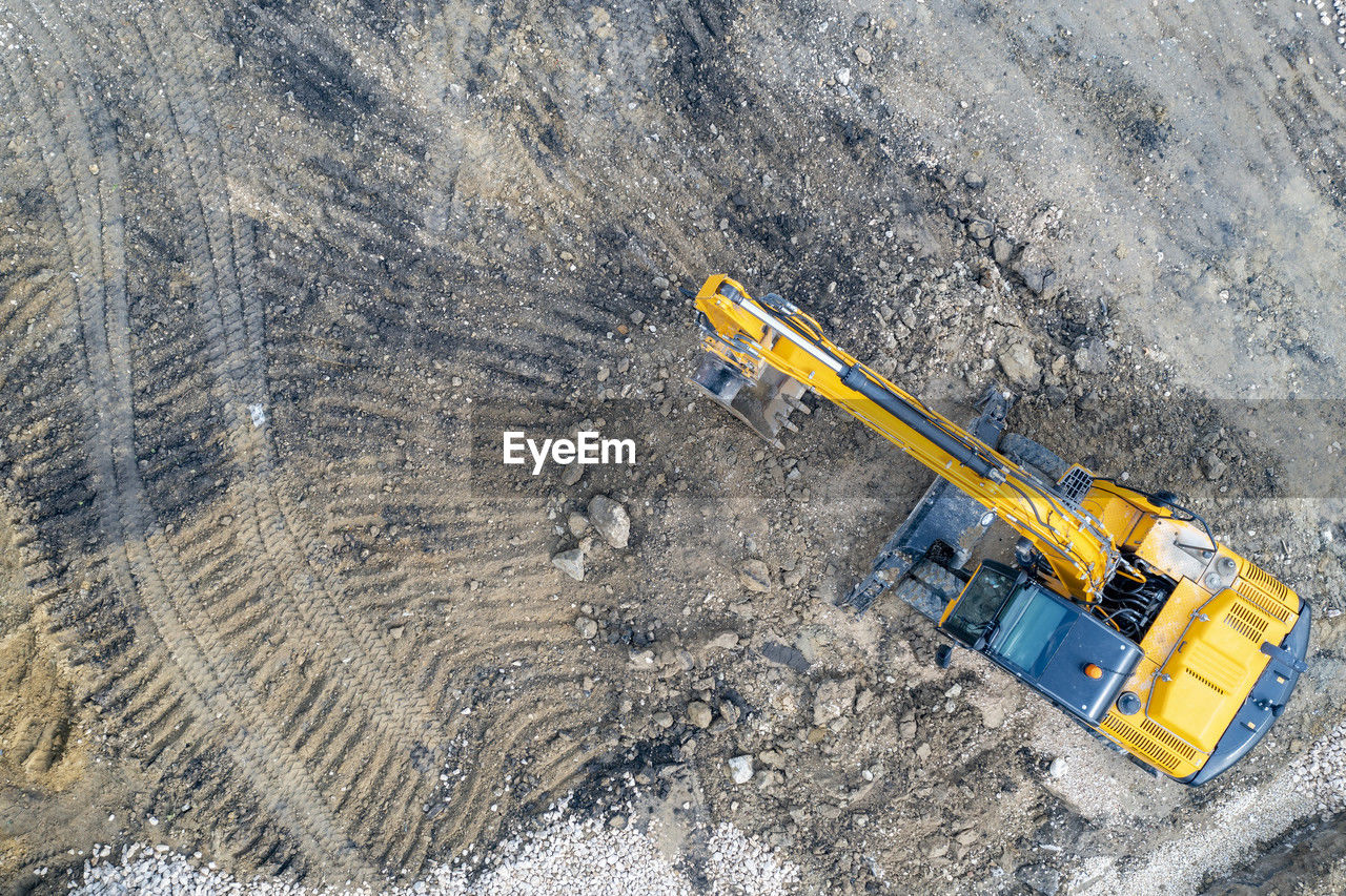 Aerial view of the stopped yellow excavator at a construction site
