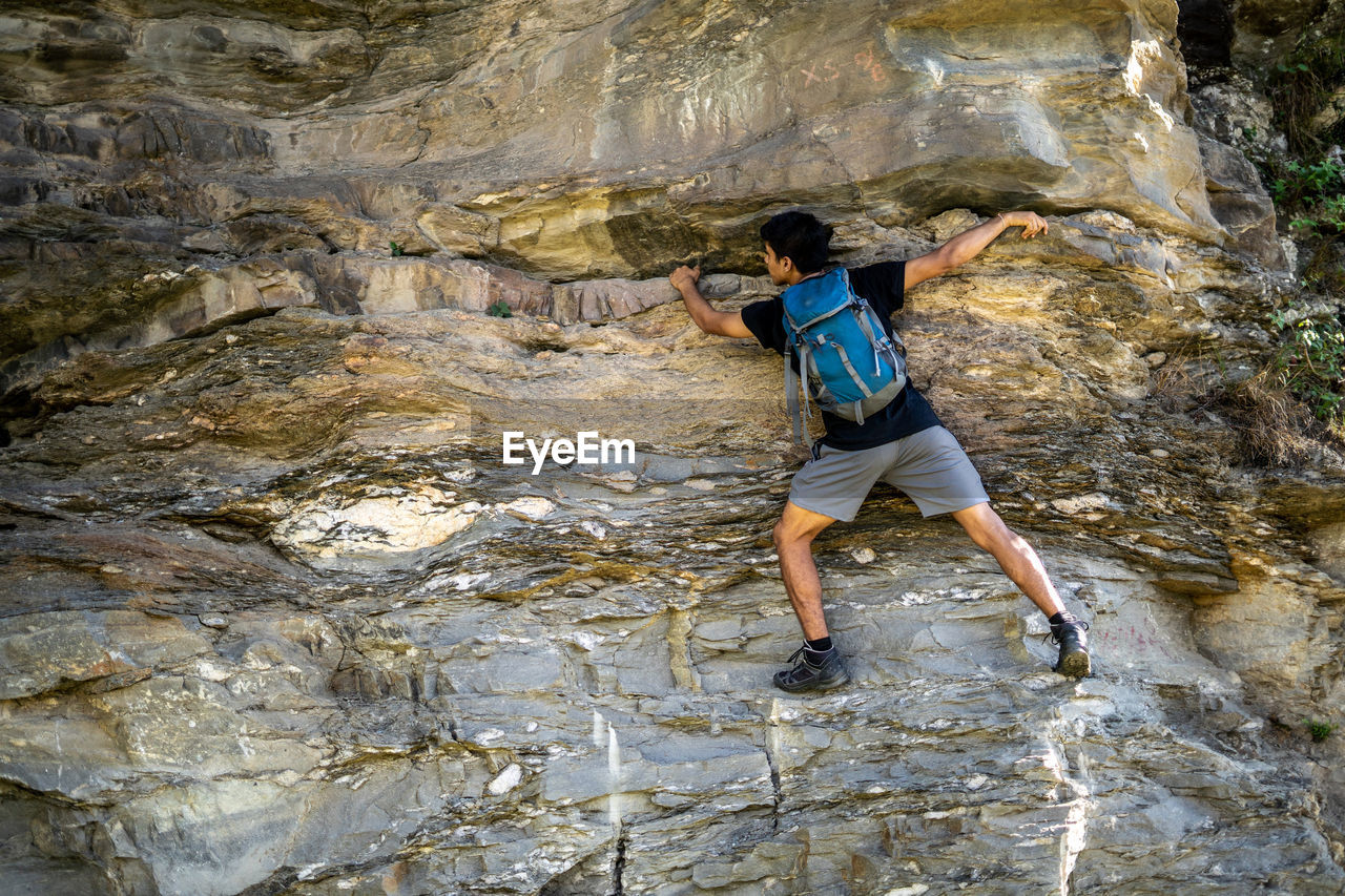 Rear view of man climbing on rock