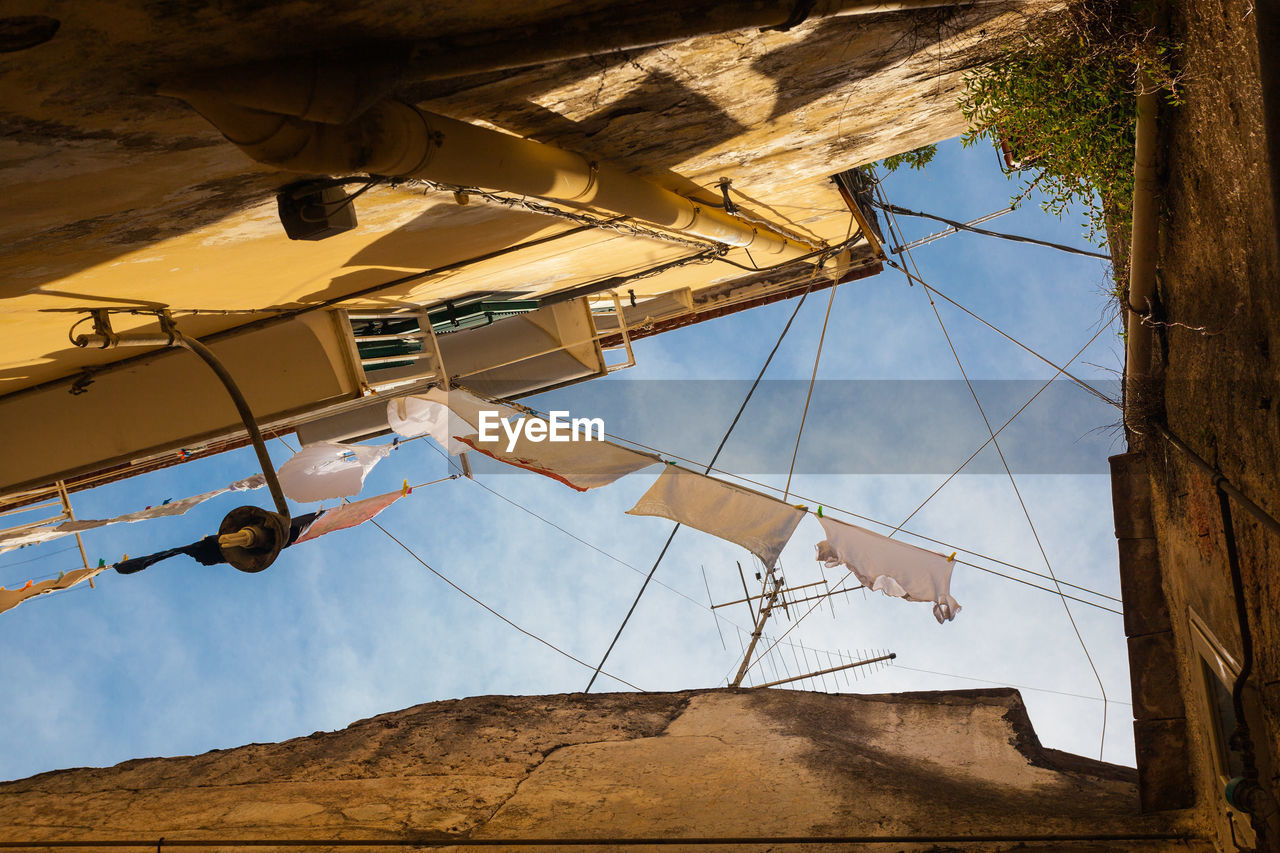 LOW ANGLE VIEW OF CRANES AGAINST BLUE SKY