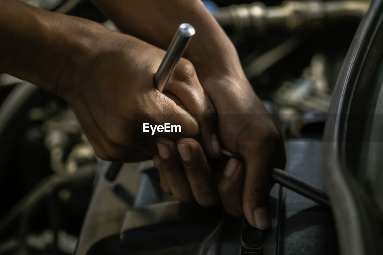 CLOSE-UP OF MAN HOLDING CIGARETTE ON CAR