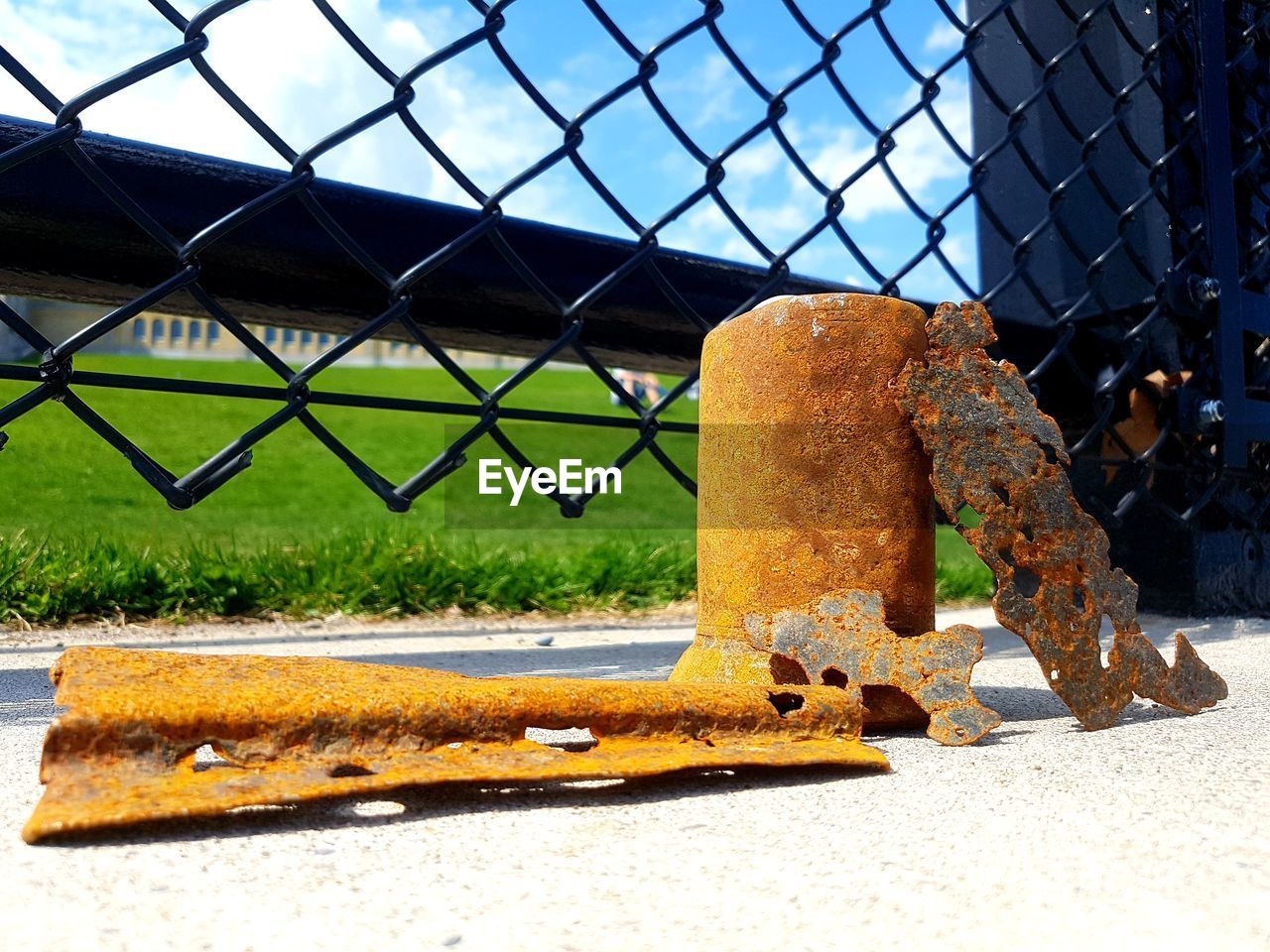 CLOSE-UP OF RUSTY METAL FENCE BY YELLOW CAR