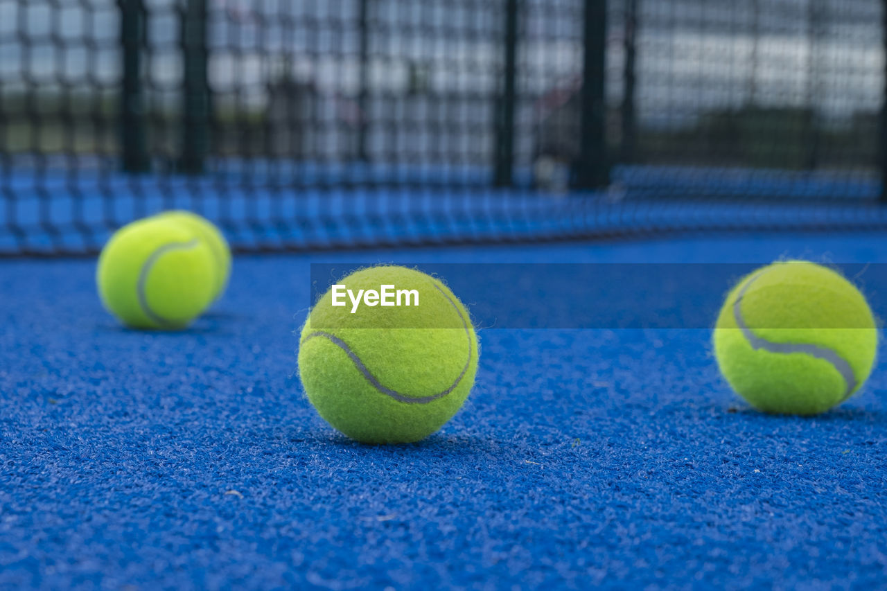 Selective focus, paddle tennis balls on a blue paddle tennis court
