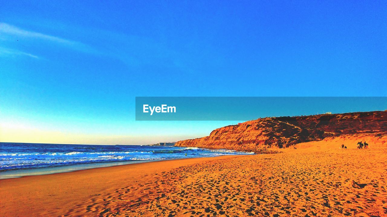 Scenic view of beach against blue sky