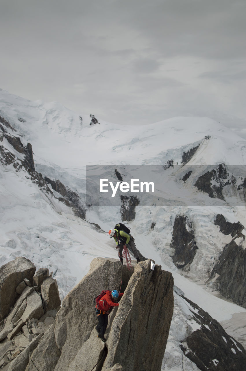 PERSON ON SNOWCAPPED MOUNTAIN AGAINST SKY