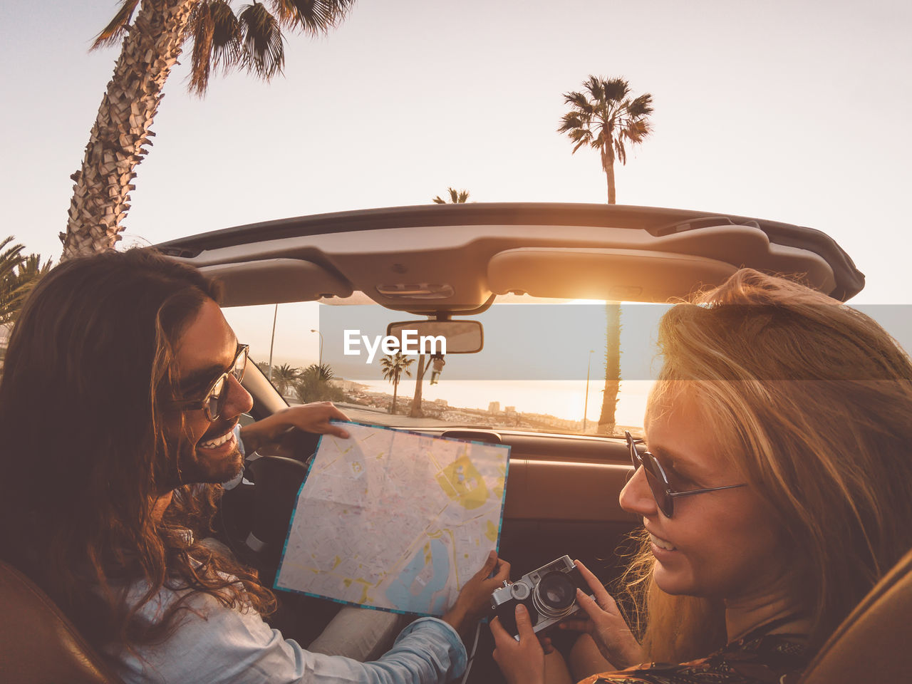 Man and woman sitting in car against sky