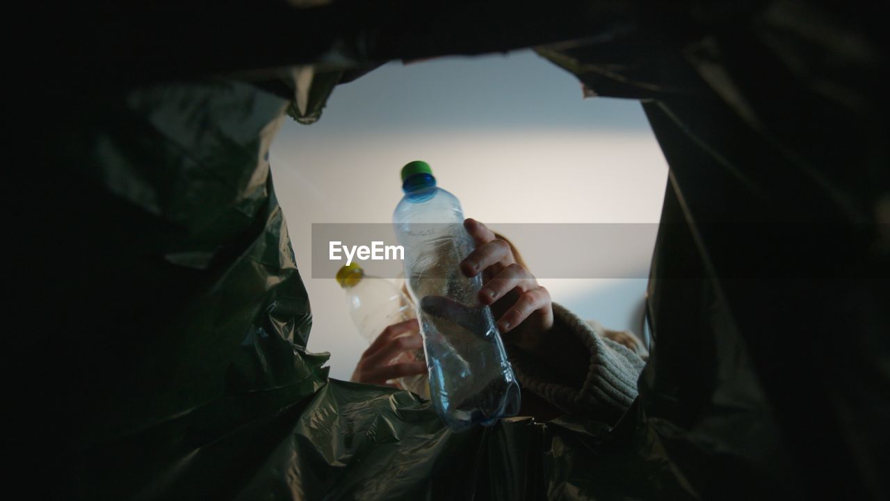 Woman throwing a plastic bottle into a trash bin. bottom view from the trash bin. eco concept 