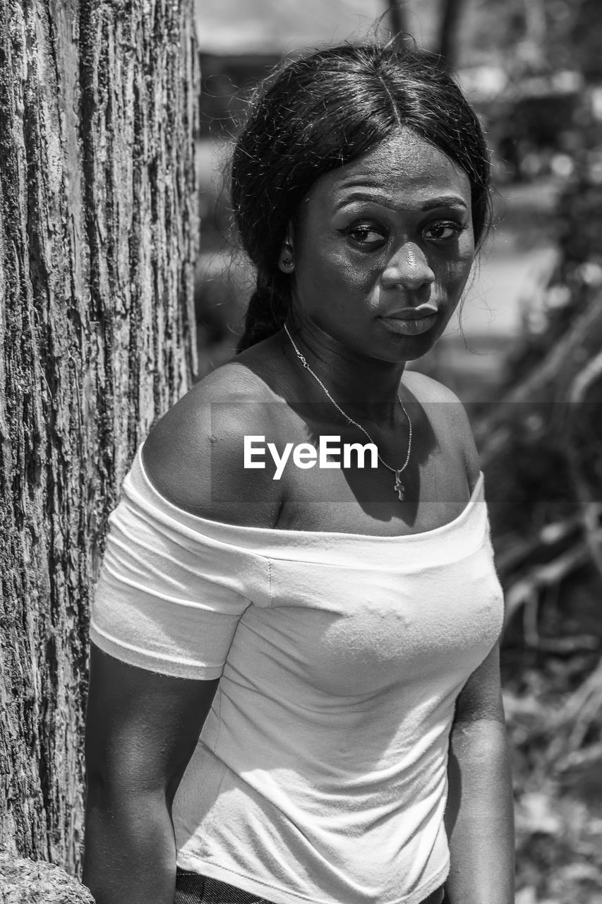 Ghana woman leans against a tree in accra and has a worried facial expression