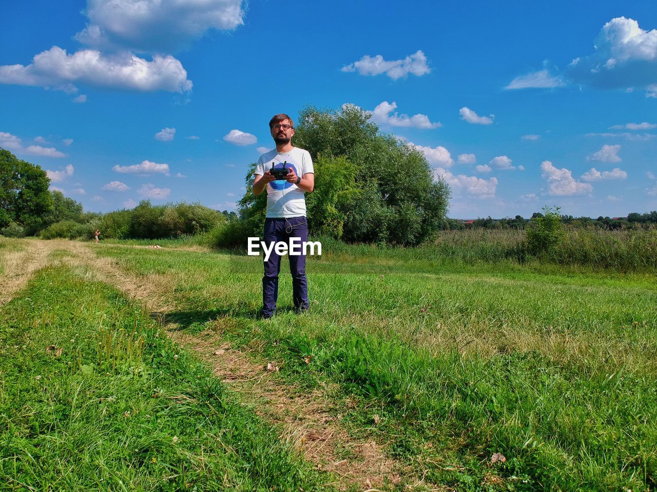 Man holding remote control while standing on land against sky