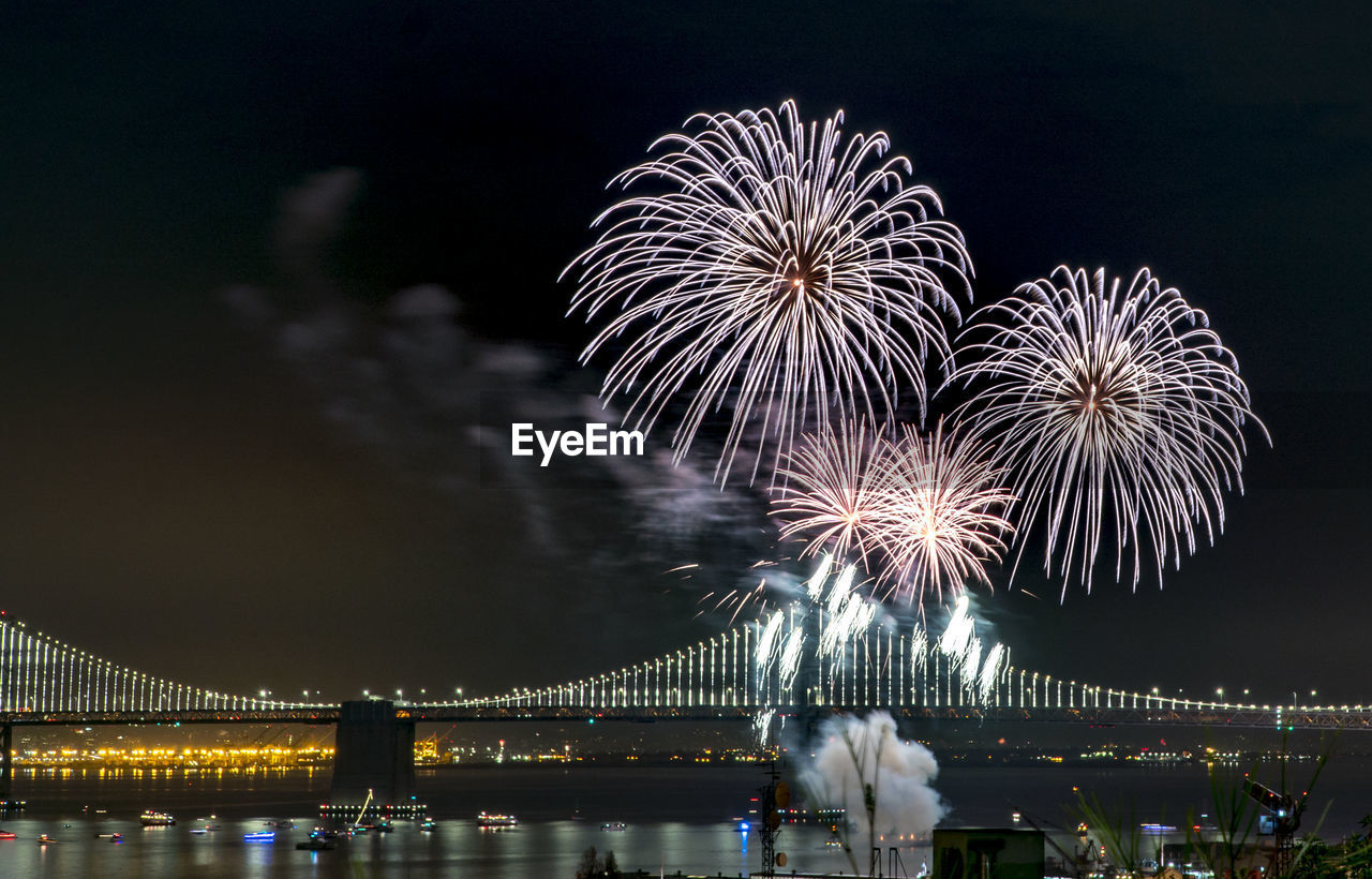 LOW ANGLE VIEW OF FIREWORK DISPLAY OVER RIVER