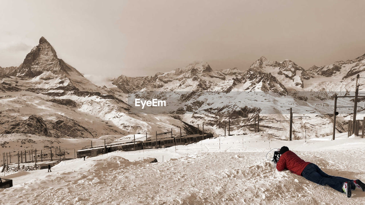 Full length of man lying on snow covered land during winter