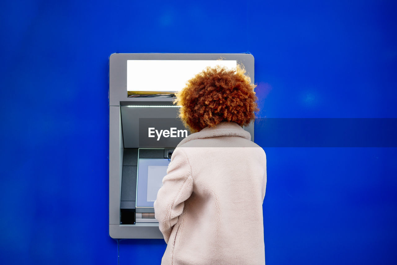 Mid adult woman with afro hair using kiosk in city