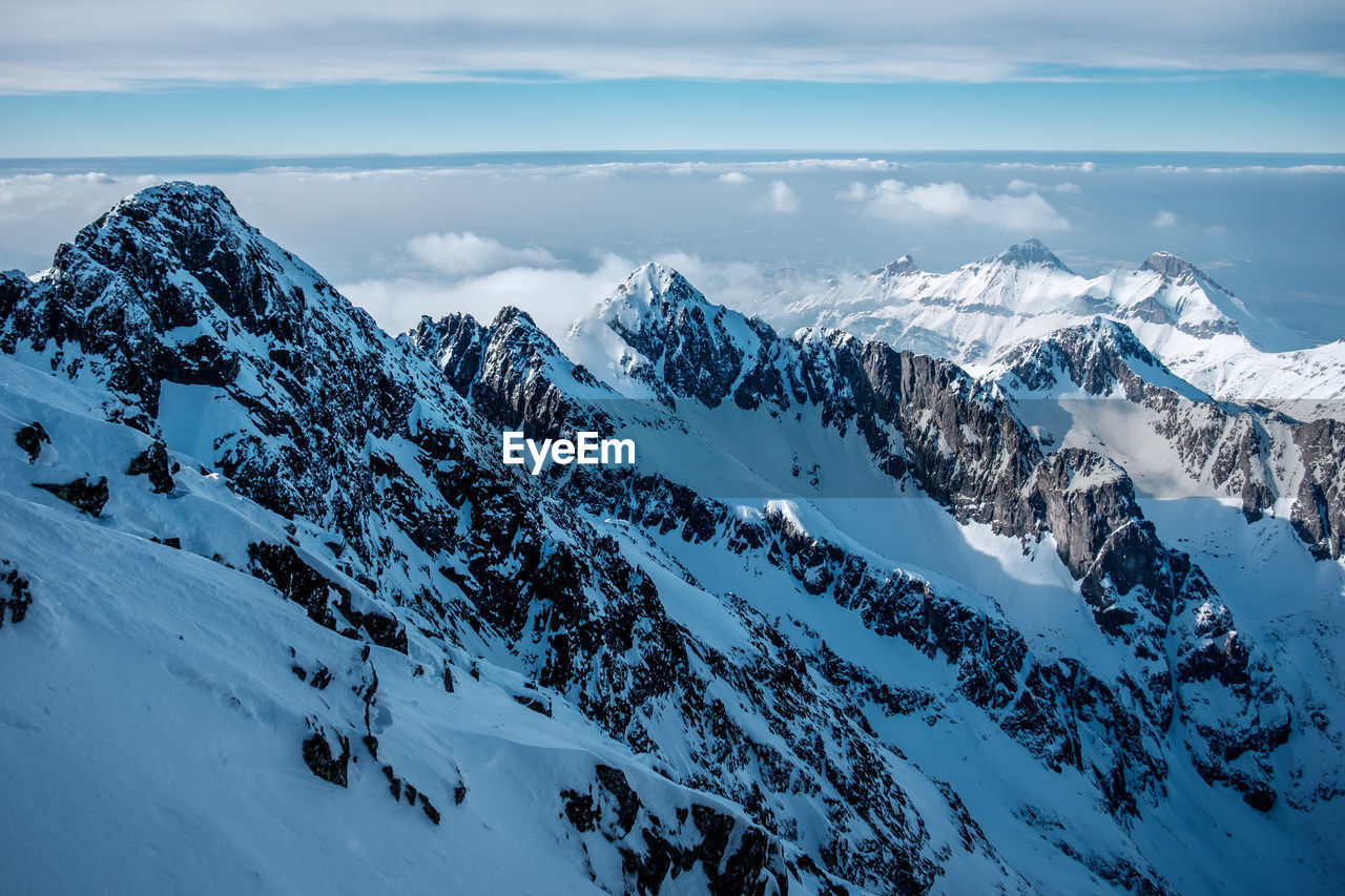 Scenic view of snowcapped mountains against cloudy sky