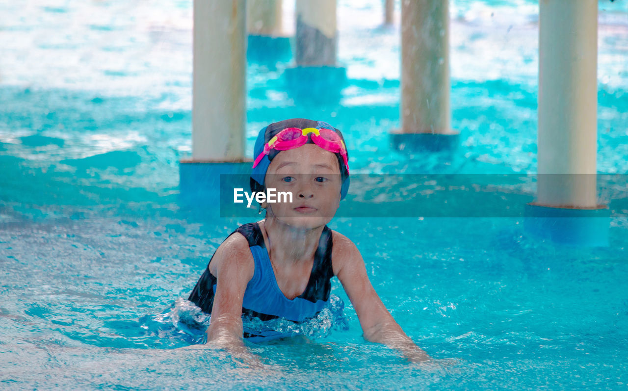 Cute girl standing in swimming pool