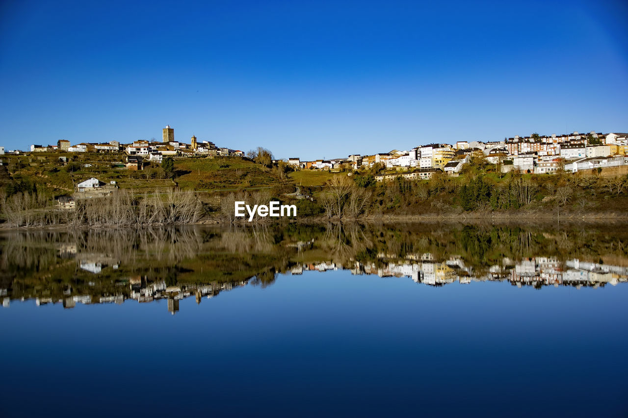 reflection, water, nature, sky, dusk, blue, lake, clear sky, evening, scenics - nature, horizon, beauty in nature, no people, tranquility, environment, landscape, mountain, travel destinations, architecture, tranquil scene, land, building, travel, outdoors, tree, sunlight, plant, standing water, tourism, cloud, copy space, city