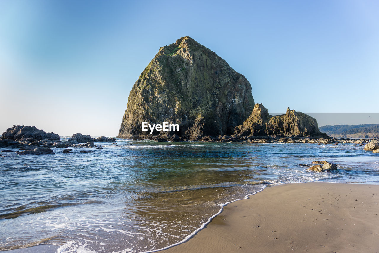 Rock formation on beach against clear blue sky