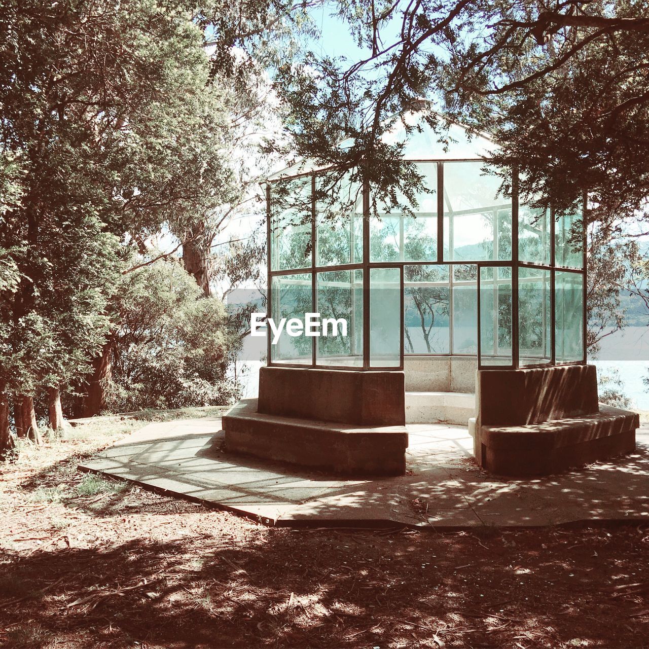 Empty glass gazebo by trees