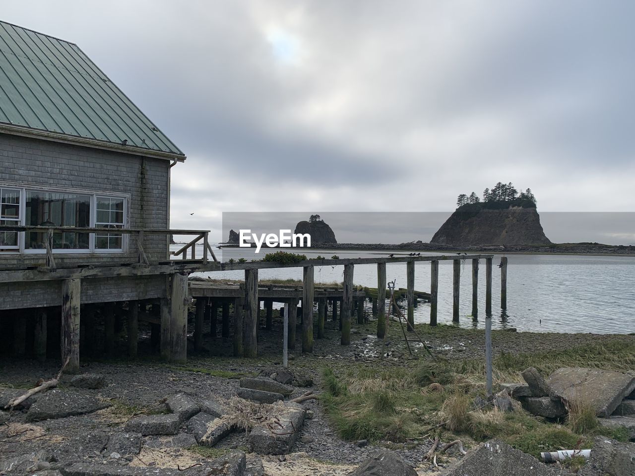 OLD HOUSE ON BEACH BY BUILDING AGAINST SKY