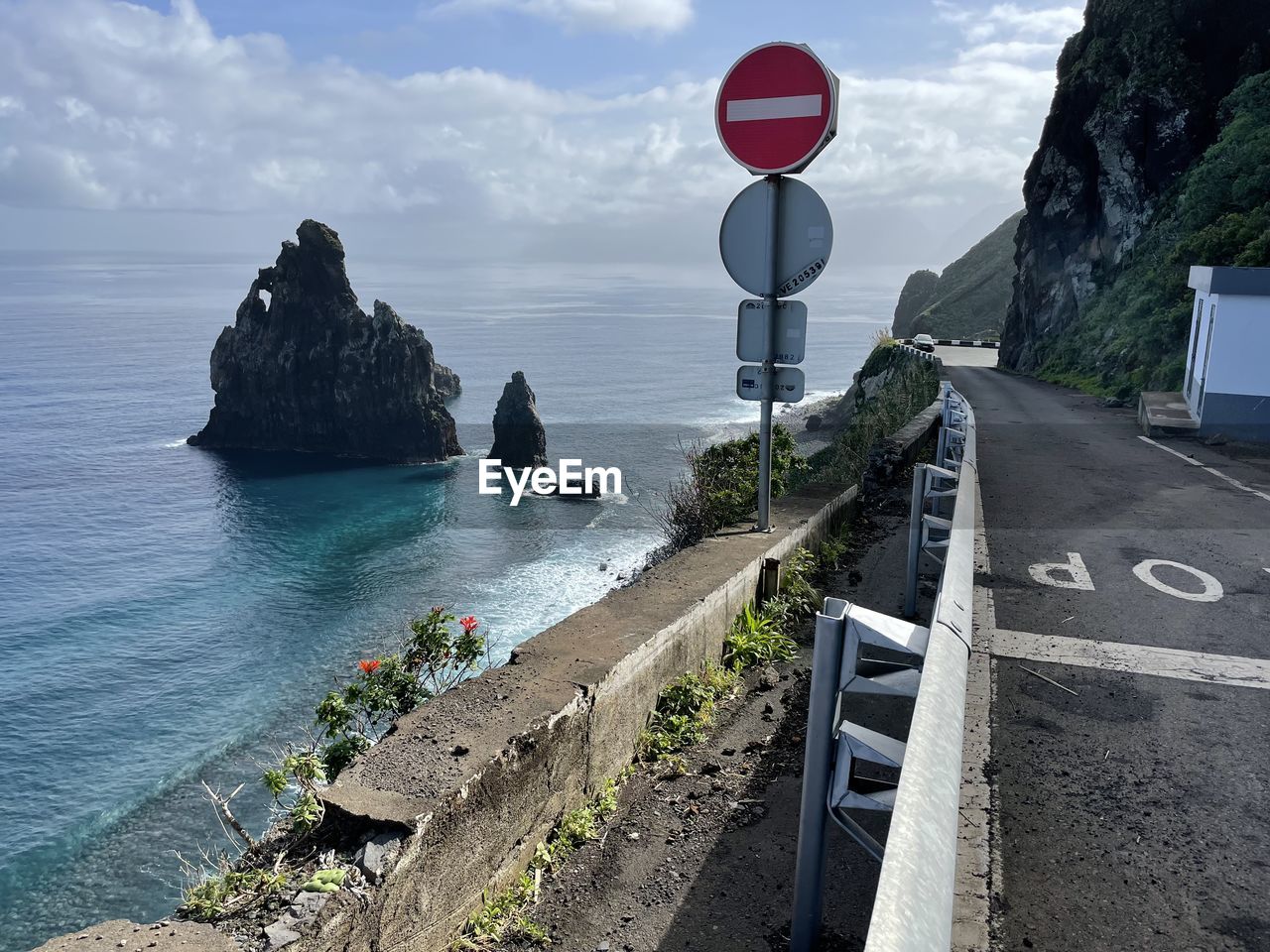 coast, water, sea, sky, sign, nature, communication, road, beach, road sign, land, transportation, terrain, guidance, vacation, cliff, scenics - nature, cloud, beauty in nature, ocean, rock, day, no people, outdoors, travel destinations, architecture, tranquility, symbol, travel, shore, body of water, city, coastline, bay, high angle view, tranquil scene, tower, tourism, horizon over water