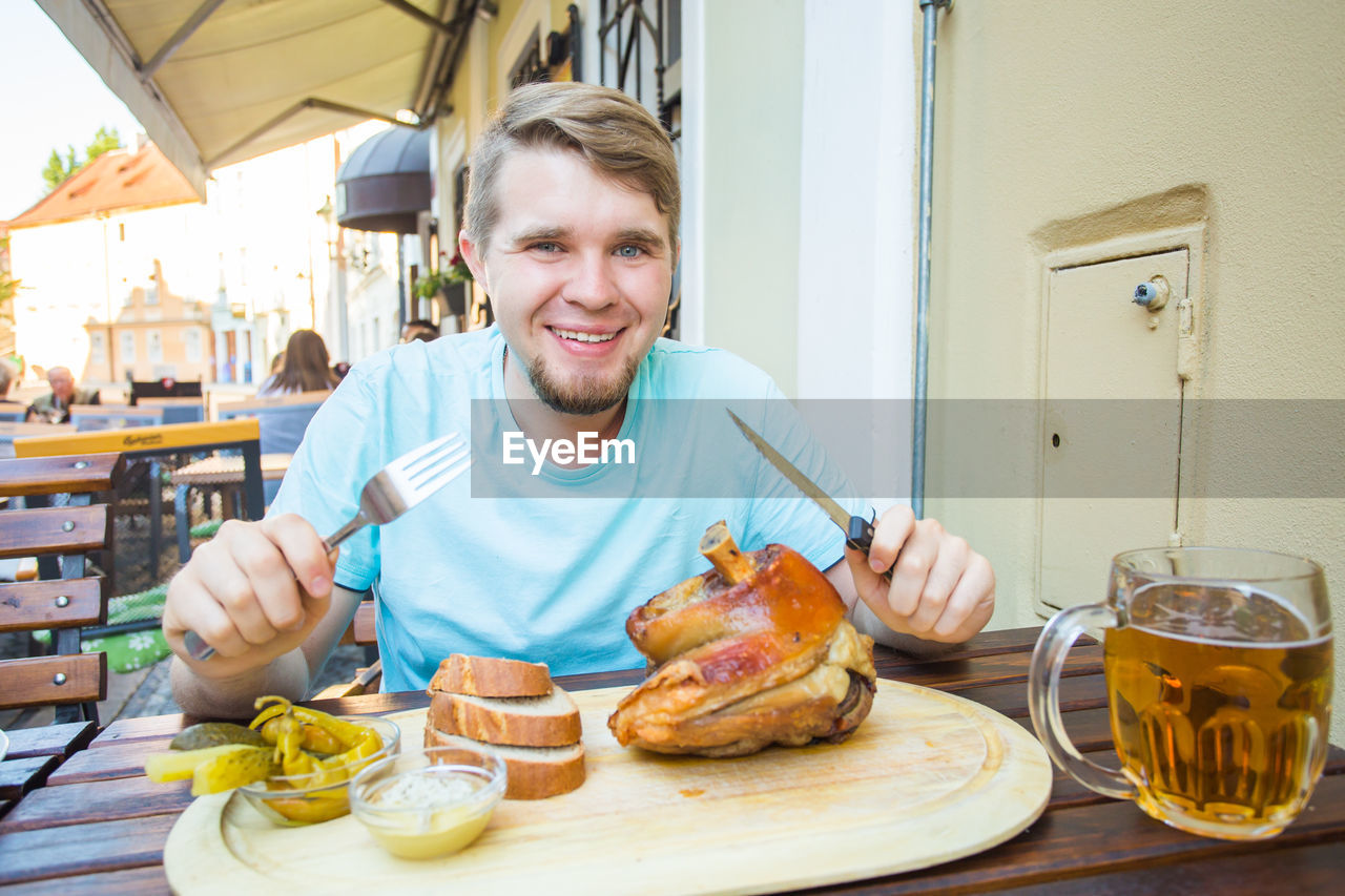 PORTRAIT OF A SMILING YOUNG MAN HAVING FOOD