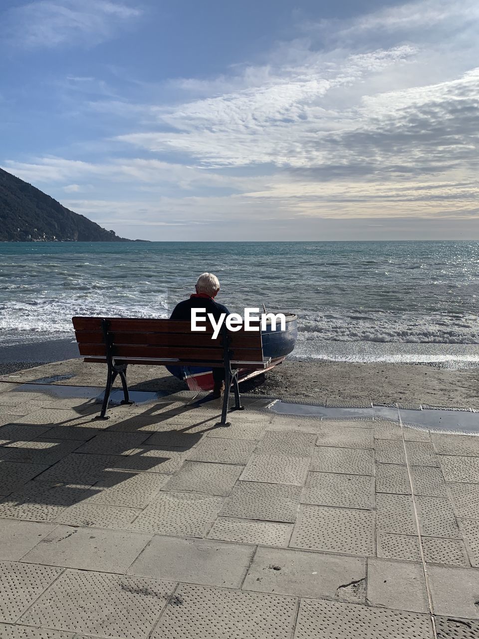 Rear view of man sitting on bench at beach