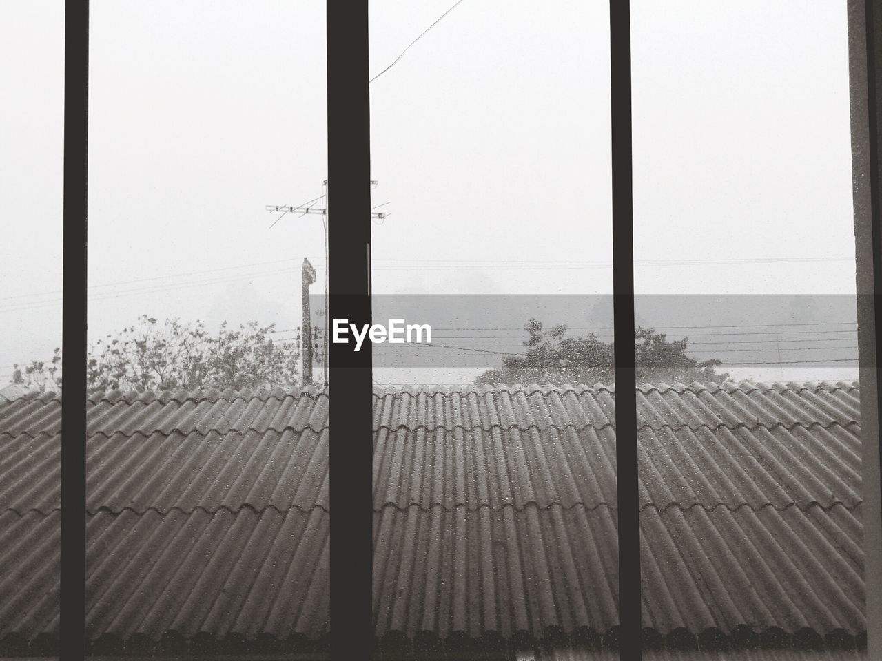 Roof of house seen through wet glass window during monsoon