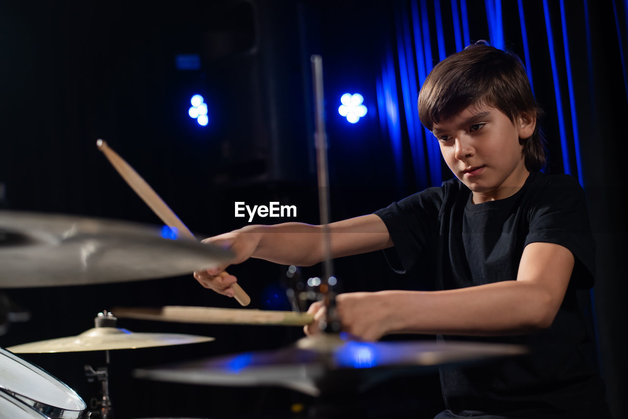 Close-up of boy playing drum at music concert