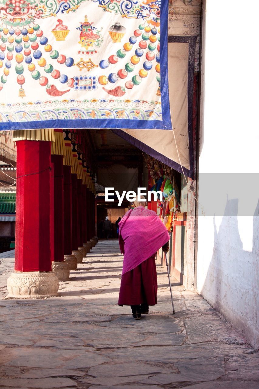 Full length rear view of monk walking in temple