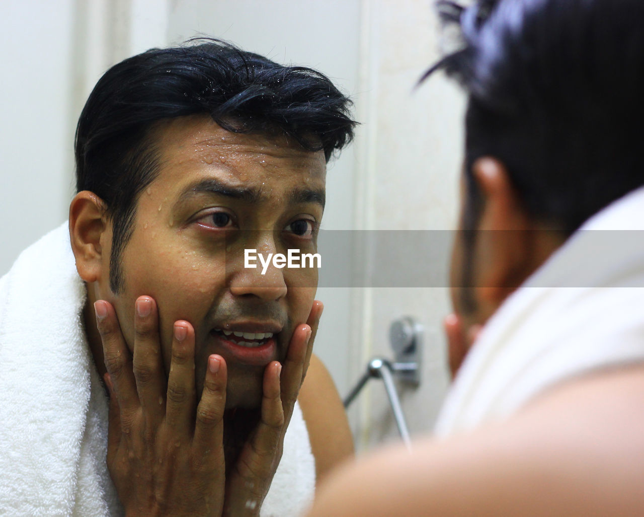 Close-up of wet man looking his reflection in mirror at bathroom