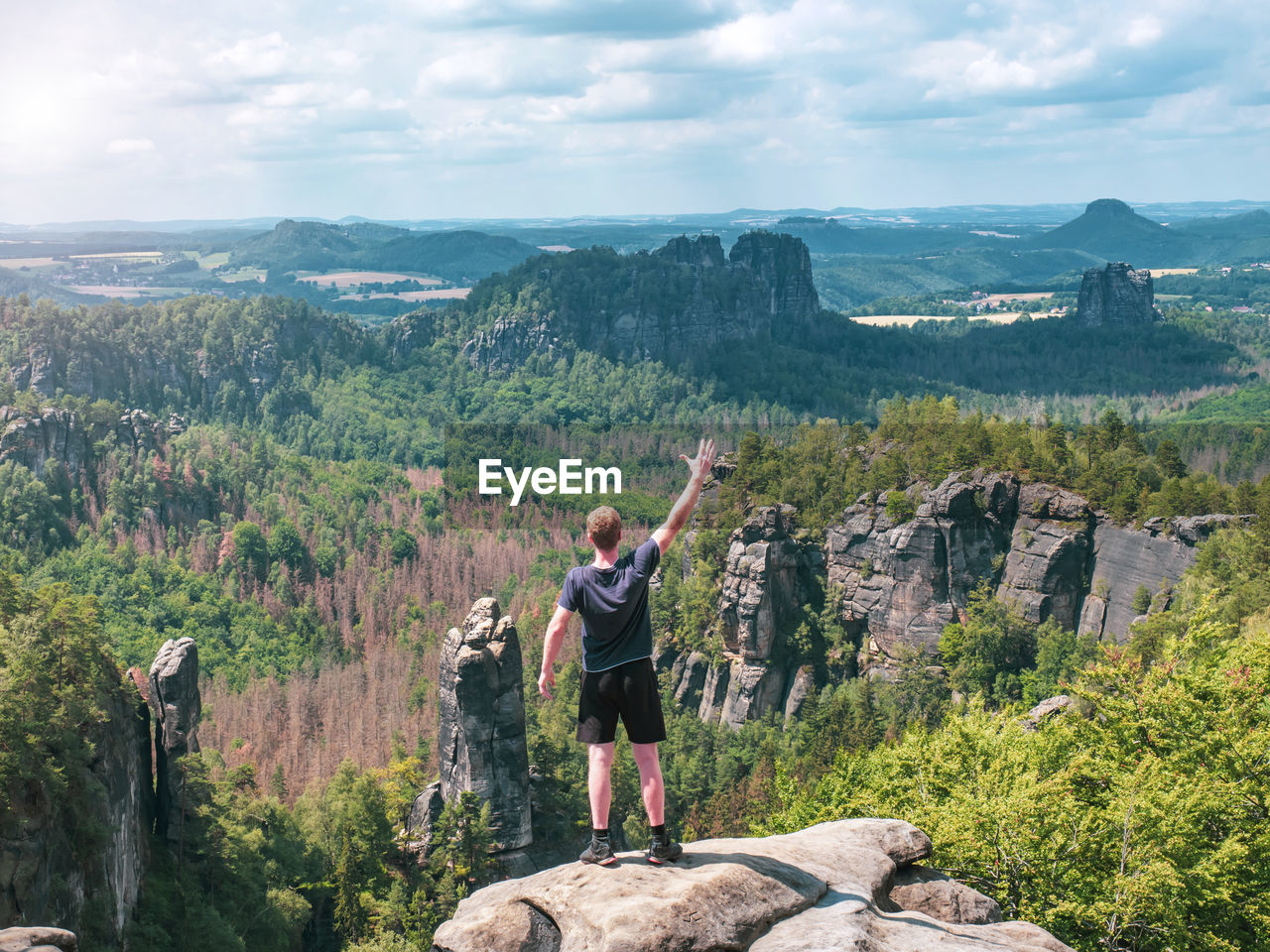 Hiker shouts to valley bellow carolafelsen rock, jagged mountains schrammsteine and falkenstein