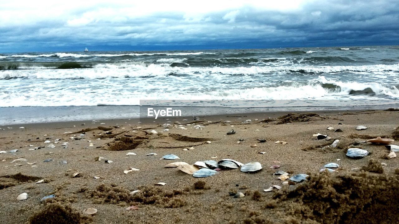 View of calm beach against cloudy sky